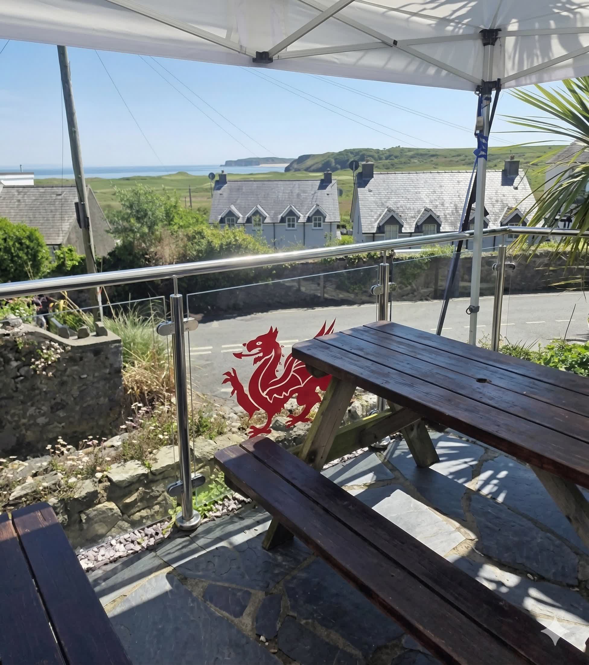 Beer garden at The Cross Inn with Welsh dragon and sea views over Carmarthen Bay